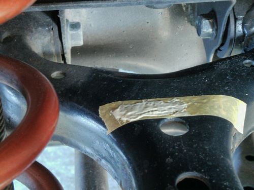 Masking tape applied to the upper control arm with a thin layer of adhesive